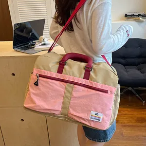 Color-blocked travel duffel bag detail showcasing durable fabric, pink front pocket and straps.