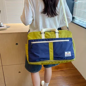 Detailed back view of a color-block travel duffel bag in green and blue with sturdy shoulder straps.