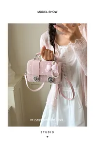 Pink polka dot small square handbag with pearl bow charm held by model in 2026 fashion style