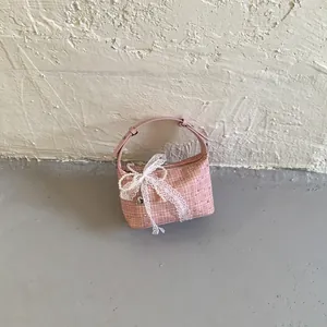 Detailed view of a pink checkered dumpling bag with delicate lace and pearl bow