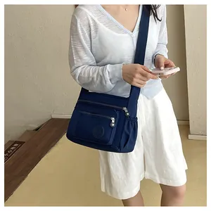 Blue nylon multi-pocket crossbody bag detail view, showing practical compartments and strap.