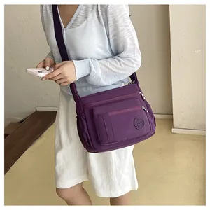 Detailed view of women purple nylon crossbody shoulder bag with multi pockets and zipper design.