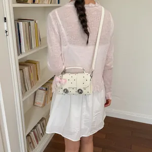 Chic white polka dot crossbody bag with cute bow charm, top handle and metal locks.