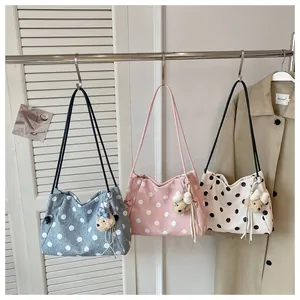 Three stylish polka dot tote bags in blue, pink, and white hanging on a metal rack