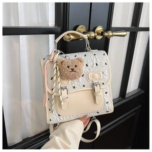 Cute preppy style backpack detail showing quilted bow print, fluffy bear pendant, and ribbons.