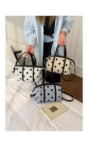 Detalle de tres elegantes bolsos de lona con lunares en blanco, crema y azul claro