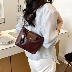 Close-up of a vintage burgundy shoulder bag on a clean counter, highlighting beaded charm.