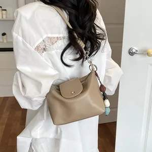Detail view of a stylish khaki hobo shoulder bag with chic flap and cute bead charm.