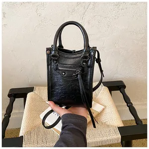 Mini sac bandoulière moto noir avec clous métalliques, poche zippée et poignée chic.