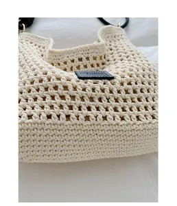 Close-up detail of cream handmade crochet tote bag with elegant black leather patch.