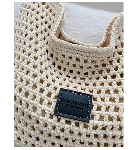 Detailed close-up of a black leather brand logo patch on a cream woven straw bag