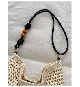 Detail shot of the black shoulder strap featuring wooden beads on a cream handmade woven bag