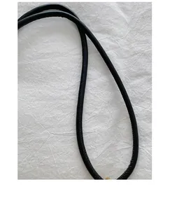 Detailed close-up view of the slim black leather-textured strap for woven tote bags