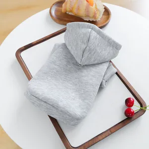 Grey pet hoodie detail shot, folded neatly on a wooden tray with cute props for pets.