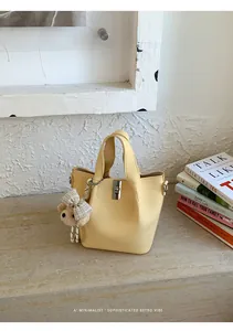 Minimalistische gele emmertas met schattige berenhanger in een lifestyle-omgeving
