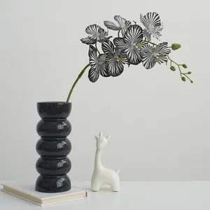 Orchidea finta con stampa zebra in vaso di ceramica nera con decorazione di giraffa.