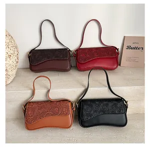 Detail of trendy French style small shoulder bag featuring embossed flap and curved base design.