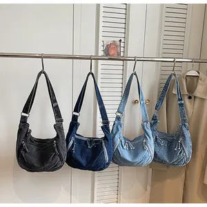 Close-up of vintage washed denim hobo shoulder bags hanging on rack showing retro style details.