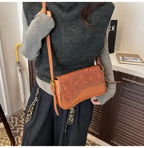Detailed shot of brown carved leather shoulder bag, vintage tooling crossbody bag design.