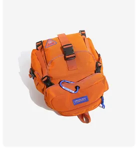 Detailansicht des orangen Outdoor-Rucksacks mit Frontschnallen und blauem Karabiner.