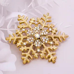 Gorgeous gold tone snowflake brooch detailed with sparkling crystal rhinestones for winter clothing.