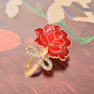 Close-up detail of the red carnation rhinestone brooch, showing exquisite enamel petals and bow.