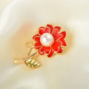 Exquisite red enamel carnation brooch with central pearl and gold-tone finish. Elegant detail.