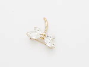 Gros plan sur la broche libellule en cristal, ailes en strass scintillantes et métal doré.