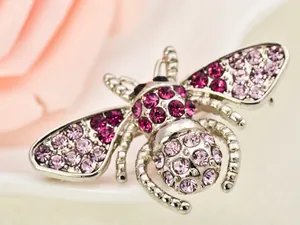 Close-up detail view of a cute rhinestone bee brooch with sparkling pink crystals.