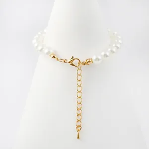 Vista detallada de un cierre de langosta dorado con cadena de extensión en una pulsera de perlas