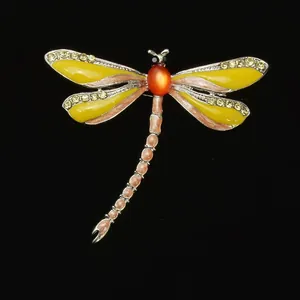 Detailed close-up of a colorful enamel and rhinestone dragonfly brooch accessory.