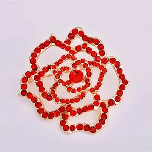 Close-up detail of the gold-tone alloy rose brooch featuring sparkling red rhinestones.