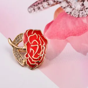 Close-up detail view of exquisite red flower brooch featuring rhinestone leaf for apparel.