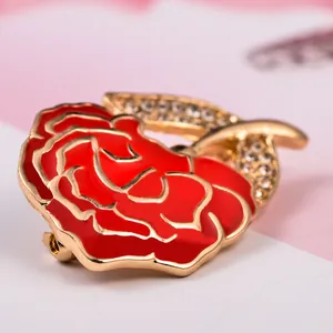 Detailed close-up of a red and gold zinc alloy carnation brooch with rhinestone leaf.