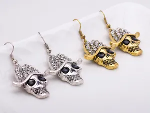 Close-up view of punk rock style skull drop earrings with rhinestone hats in silver and gold.
