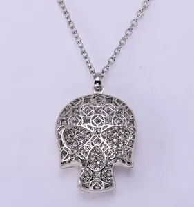 Close-up detail of silver rhinestone paved skull pendant necklace, polished metal chain.