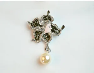 Close-up detail of vintage art nouveau style rhinestone enamel woman face brooch with pearl drop.