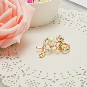 Elegant gold-tone LOVE letter brooch featuring a lustrous pearl and sparkling crystal stones.