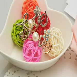 Close-up detail of stylish alloy rhinestone pearl LOVE letter brooch in decorative bowl