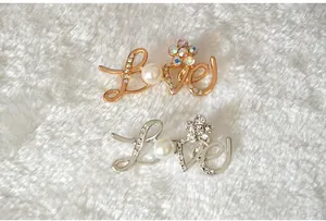 Close up detail of fashionable Korean style LOVE rhinestone letter brooch in gold and silver colors.