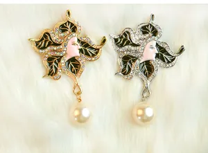 Close up detail of vintage artistic face brooch featuring sparkling rhinestones and pearl pendant.