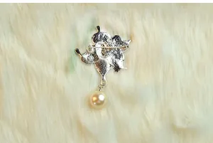 Vintage face brooch detail showing metal pin structure and elegant pearl pendant accessory.