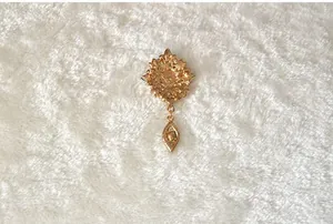 Detail view of the vintage gold-toned crystal brooch, showcasing intricate floral metalwork.