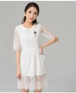Close-up detail of elegant white lace dress featuring a vintage green crystal brooch accessory.
