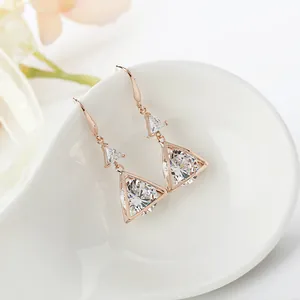 Close-up detail of elegant rose gold geometric triangle cubic zirconia drop earrings.