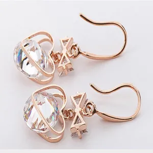 Detailed view of fashion rose gold heart zirconia drop earrings with bow charm close-up.