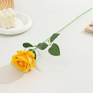 Close-up detail of a single yellow artificial flannel rose with green stem and leaves.