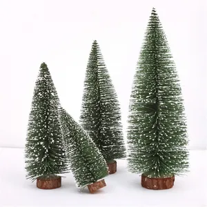 Détail de mini sapin de Noël de bureau avec des aiguilles floquées de neige et base bois.