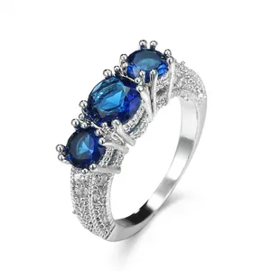 Detailaufnahme eines silberfarbenen Rings mit drei blauen Zirkoniasteinen und Pave-Besatz.