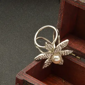 Detalle anillo bufanda pedrería, clip chal metal plateado perla, primer plano accesorio.
